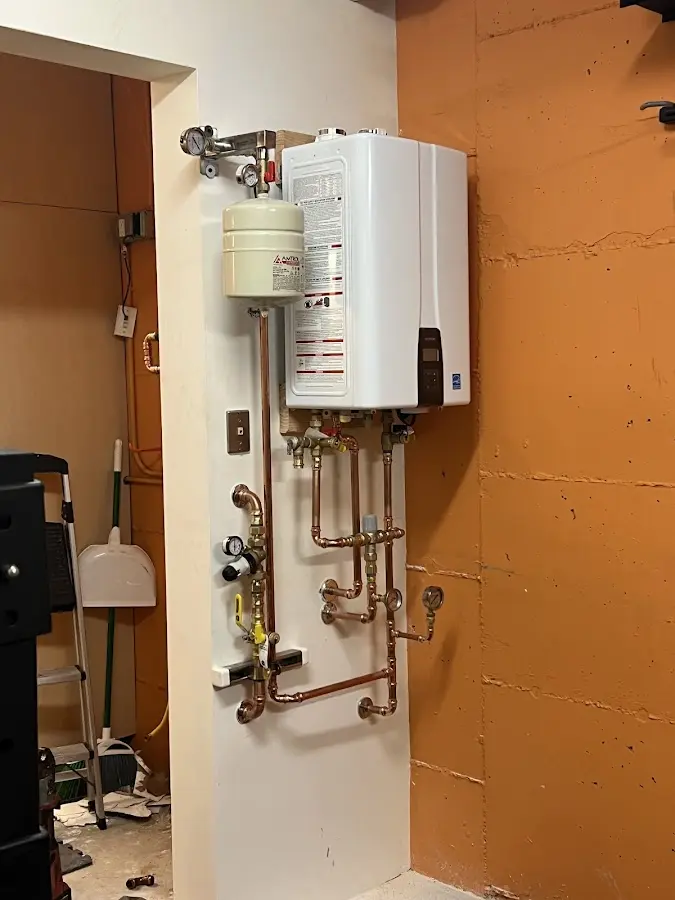 Plumbing technician inspecting water heater connections in Little Ferry